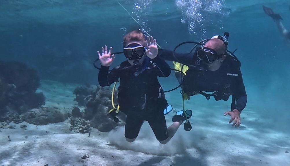 Beginner scuba diver exploring a shallow reef in Roatan with an instructor nearby